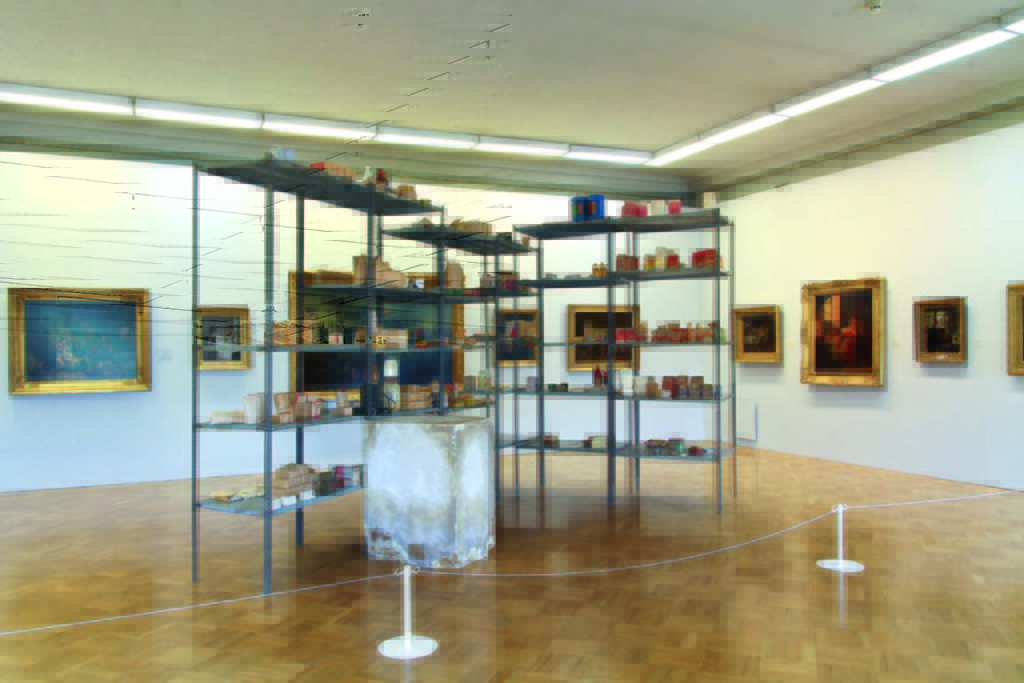 Joseph Beuys. Wirtschaftswerte (Economic Values). 1980. Iron  shelves with basic food and tools from East Germany; plaster  block with pencil and fat; paintings from the collection of  the host museum. Shelves: 290 × 400 × 265 cm; Plaster  block: 98.5 × 55.5 × 77.5 cm. Collection of S.M.A.K. Stedelijk  Museum voor Actuele Kunst, Ghent, Belgium. Installation view,  MANIFESTA 10, Winter Palace, State Hermitage Museum.